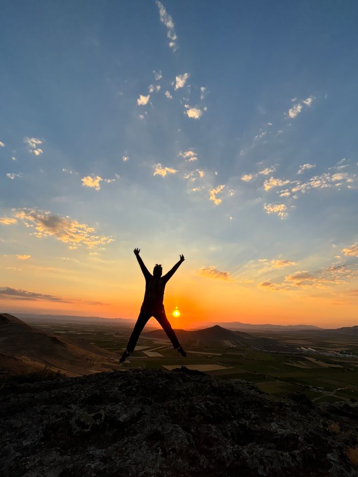 A person silhouetted against a vibrant sunset on a mountain peak, symbolizing freedom and adventure.