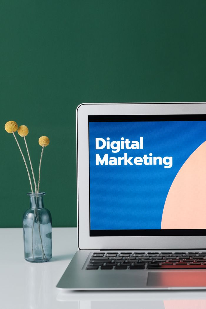 Home A laptop displaying 'Digital Marketing' with a minimalist floral decor in a glass vase.
