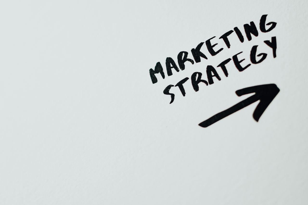 Menus Close-up of handwritten 'Marketing Strategy' text with an arrow on white background.